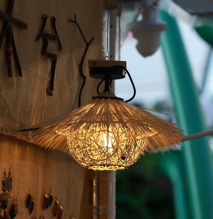 A rustic straw lamp provides warm lighting in a cozy indoor setting with natural decor.